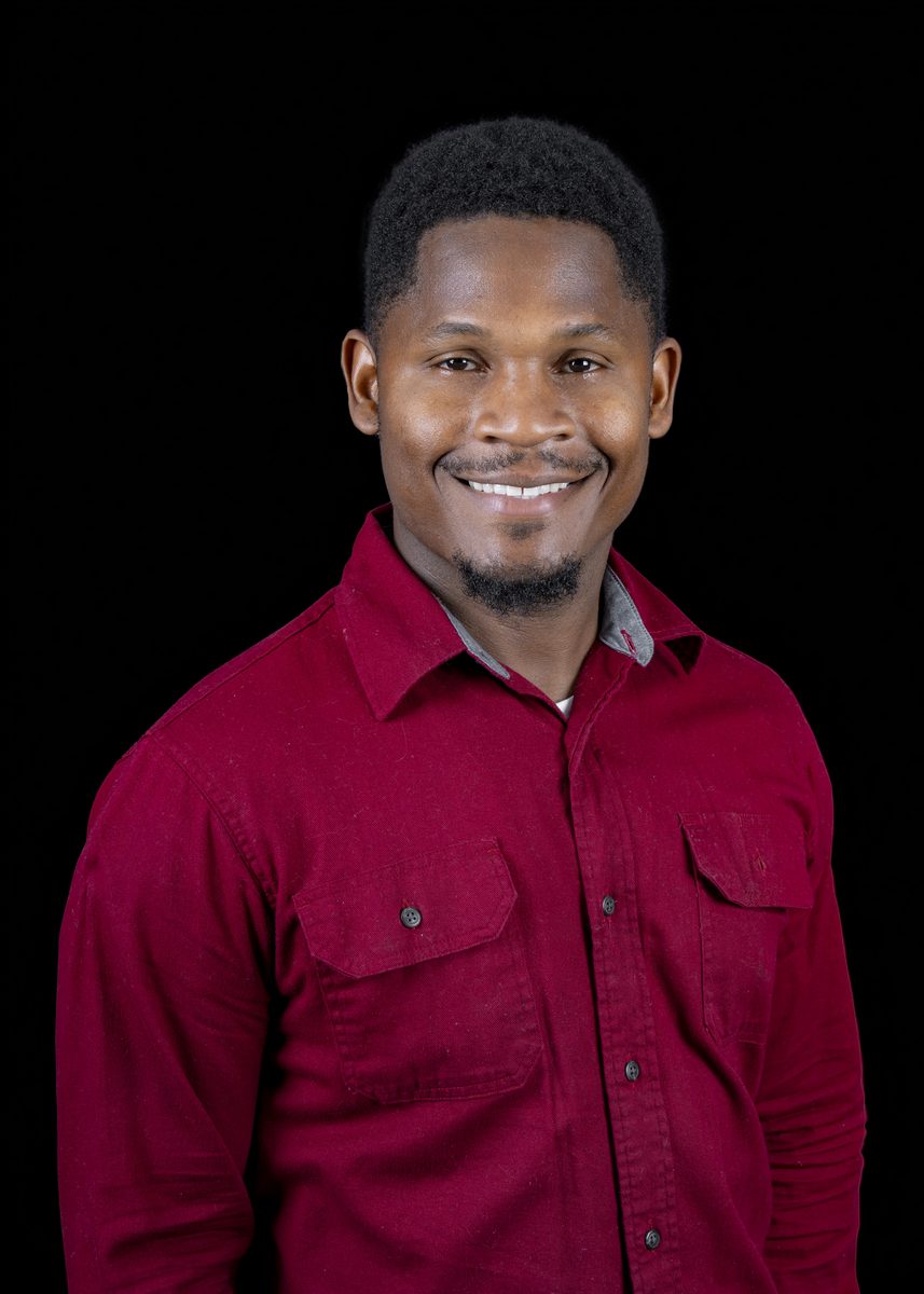 Moncha 'Delroy' Hymans, owner of Mr GC Services LLC, smiling in a red button-up shirt
